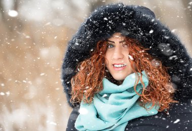 Kırmızı kıvırcık saçlı güzel kız kar düşüyor gibi poz