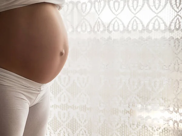 Belly of a pregnant woman on a white background