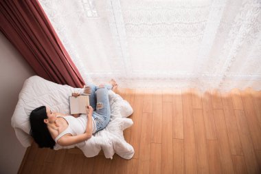 Güzel cam kenarında yere yatan kız ve bir kitap okumak