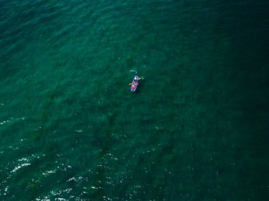 Kürekleri okyanusta, havadan çekilen küçük bir tekne.