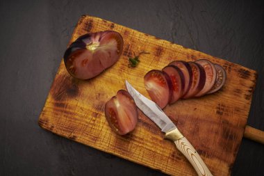 Grup dilimlenmiş raf domates ve eski ahşap kesme tahtası üzerinde bıçak