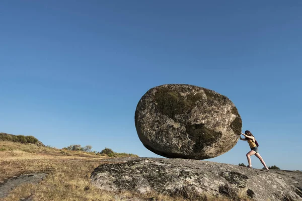 Mujer empujando una roca del mundo. Metáfora del esfuerzo de las mujeres trabajadoras. El nuevo Sísifo es una mujer Fotos de stock libres de derechos