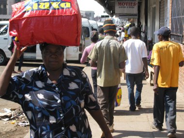 Harare, Zimbabwe, 7october 2015.A sttreet sahne bir kadın yakaladığında bavulunu onun baş bwhilst bir cadde boyunca yürüyüş üzerinde gösterilen.