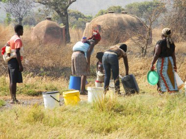  Marondera, Zimbabwe, 24august 2017.A grup Afrika kırsal kadınların bazı çocuğun tek bir alma sırtlarına su ile kullanarak dokunun kovaları.                            