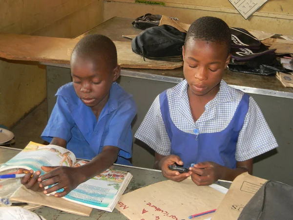 Norton, Zimbabwe, 20 Temmuz 2016. Onun sınıf arkadaşı bir kitap okur iken sınıf cep telefonu tarama birincil liseli.                              