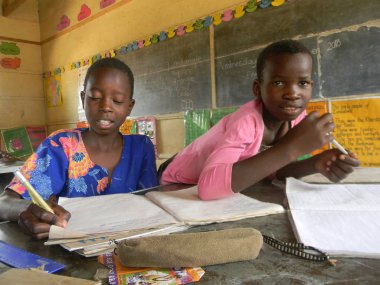      Norton, Zimbabwe, 23 Ekim 2018. Yakın çekim bir birincil okul çocuğu ve kız bir egzersiz yaparken bir sınıf içinde bir masa üzerine oturmuş kitap yazma.                           