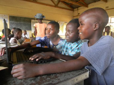  Norton Zimbabwe, 23 Ekim 2018. Sınıf sahnesinde üç tane gülümseyen ilkokul çocuğu bir sınıfta dizüstü bilgisayar kullanırken görülüyor.,                              