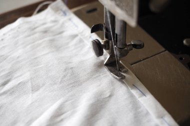 Antika dikiş makinesi, eteklerine kadar yakın ve beyaz pamuklu kumaş