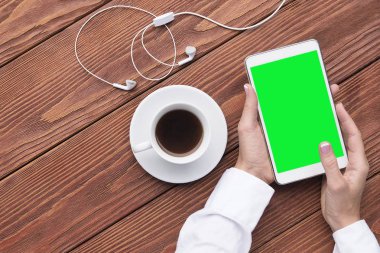 Fincan kahve ve mockup dijital tablet ve kahverengi ahşap masa üzerinde kulaklık ile eller. Kahve molası. Yakın çekim, görünümü top