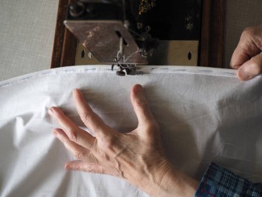 Dikiş işlemi. Ayak eski vintage dikiş makinesi ve yaşlı kadının elleri. Seçici odak