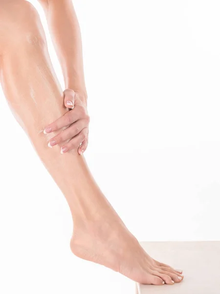 Женские руки массаж ноги женщины с лосьоном для тела, закрыть — стоковое фото