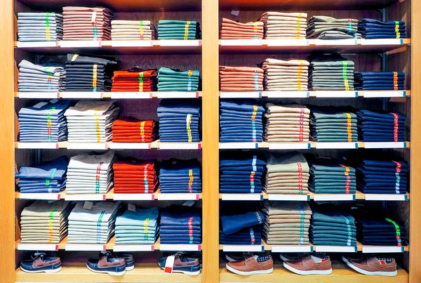 Schappen met T-shirts en sneakers in een grote kledingwinkel — Stockfoto