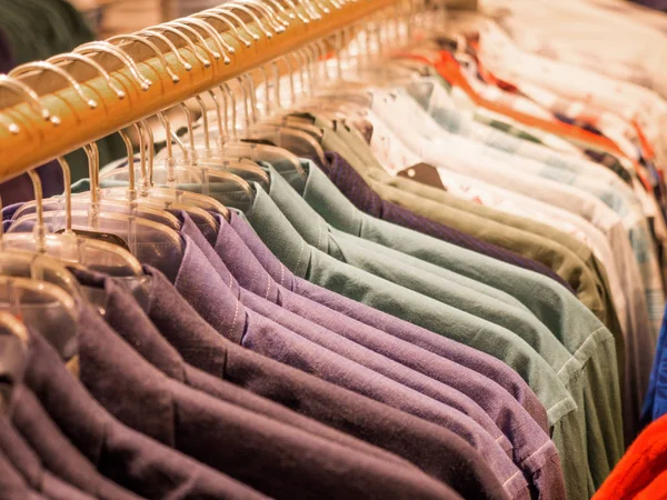 Сорочки різних кольорів на вішалці в магазині. Стійка для одягу в магазині чоловічого одягу, акції — стокове фото