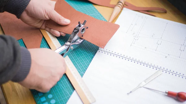 Tanners hands at work with revolver punch, awl and leather. Selected focus, close up. — Stock Photo, Image