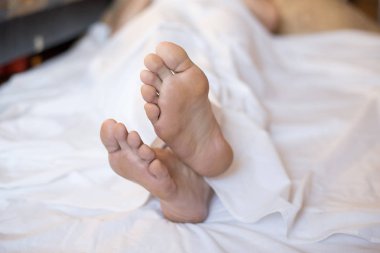Bir yatakta erkek çıplak ayakla beyaz keten, seçilen odak