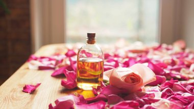 Aroma yağı pembe gül ve gül yaprakları ahşap yüzeyine, seçilen odak ile şişe