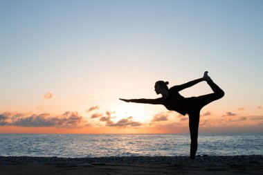 gün batımında sahilde otantik yoga uygulamak kadın silüeti