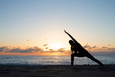 Yoga sahilde akşamları yaparken insan silueti