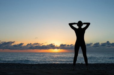 İnsan siluet duran deniz kıyısında ve ayarı güneşe bakarak