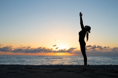 İnsan siluet şafak kumsalda yoga yaparken
