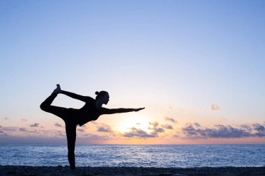 gün batımında sahilde otantik yoga uygulamak kadın silüeti