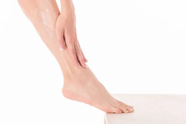 Женские пальцы с французским маникюром наносят крем на ногу, закрывают — стоковое фото