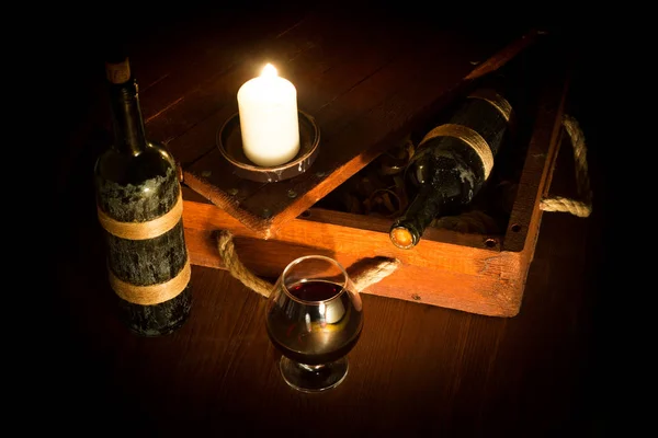 Natureza morta da caixa de madeira antiga atmosférica com vinho tinto vintage, vidro e uma vela, chave baixa, foco selecionado . — Fotografia de Stock