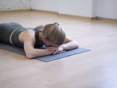 Yorgun insan. Egzersizler arasında kısa nefes. Rahatlatıcı pozda paspasın üzerine yatan kadın, yerde yüz, seçici odak