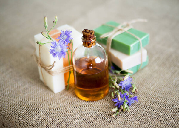 Натуральное мыло и бутылка ароматного масла на джутовом фоне. Набор органических косметических средств, селективная направленность
