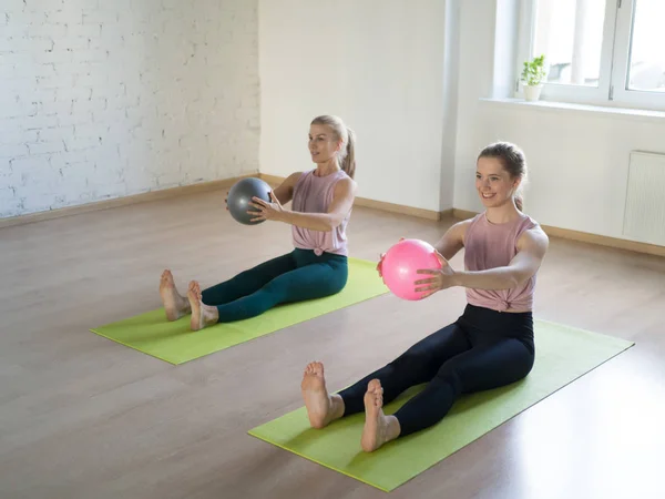İki beyaz kız fitness stüdyosu, loft tarzı, seçici odak, küçük fit topları ile pilates pratik.