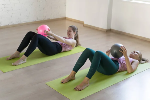 Fitness stüdyosunda komik çekim. İki beyaz kadın fit topları ile pilates yapıyor ve bir kız yorgun ve eğitim durdurmak, seçici odak.