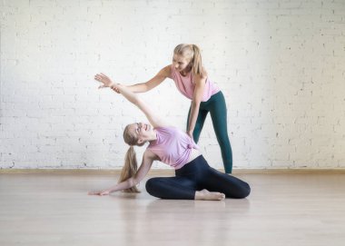 Fitness stüdyosunda kişisel antrenör ile pilates egzersiz. Denizkızı pozu yapan beyaz kız, eğitmen doğru tekniği, seçici odak.