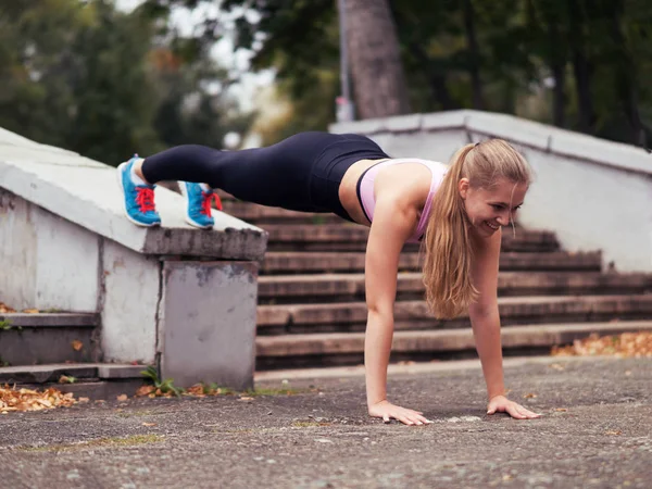 Szőke Fit lány csinál edzést a parkban kültéri nyáron, deszka pózol, szelektív fókusz — Stock Fotó