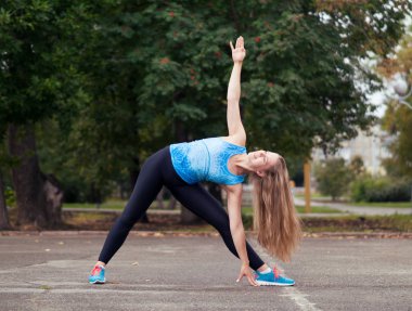 City yoga. Caucasian blond girl of medium build doing training in the urban park, selected focus