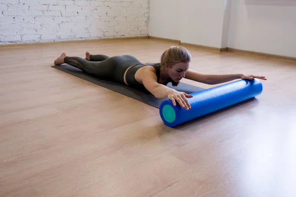 Back stretching exercise with foam roller, woman lift up her upper body, does work out in loft studio, wide angle view. — Stock Photo, Image