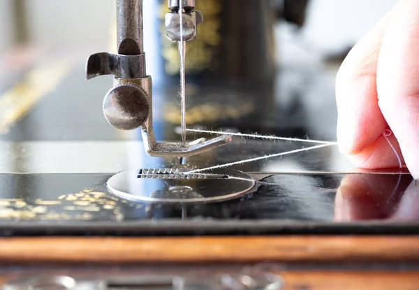 Pied pressoir de la machine à coudre manuelle antique, fermer. Les doigts des tailleurs tirent un fil, vue latérale, grain de film, mise au point sélectionnée . — Photo