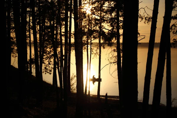 Black silhouettes of the fisherman and trees on a decline — Stock Photo, Image