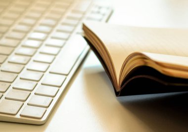 Açık bir kitap ve bir klavye masaya yakın çekim çekim vardır