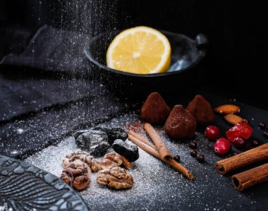 Domalan kakao tozu, tarçın, fındık ve Kuruyemiş altında siyah bir zemin üzerine pudra şekeri