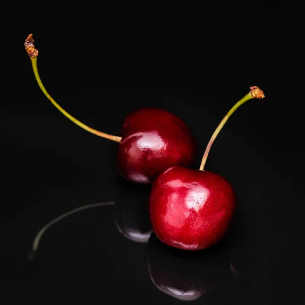 Two cherries on a black background