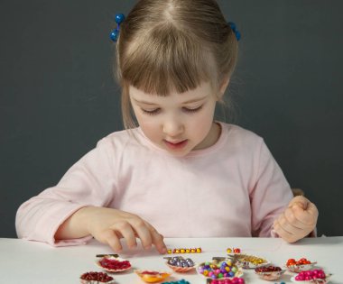 Boncuk iş parçacığı ve bilezik yapımı sevimli küçük kız