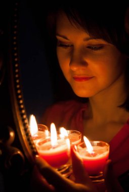 güzel genç kadın ve mumlar aynadaki yansımasıdır