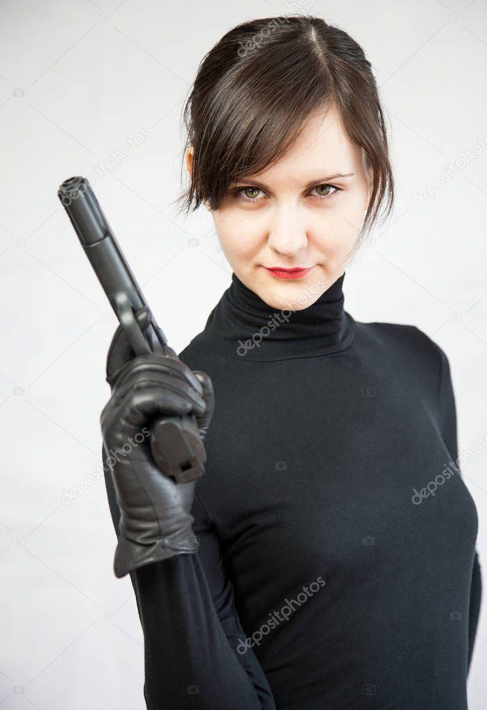 Beautiful girl holding a pistol on neutral background