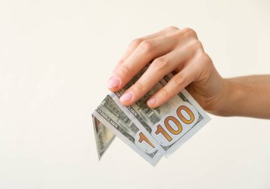 Woman's hand is holding two hundreds of dollars, neutral background clipart