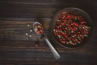 Bezelye bir kırmızı, yeşil, beyaz biber kaşık ve bir ahşap zemin üzerine bakır bir daire