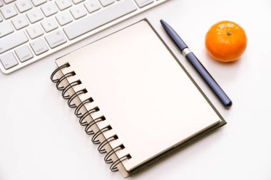 Çalışma alanı ile bir klavye ve bir beyaz masa üstünde açılan bir defter bir parçası