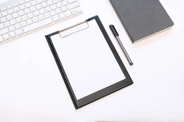 Business background: a folder with empty sheets of a paper, a keyboard and a diary. White background.