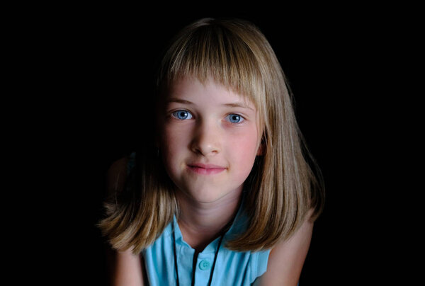 Portrait of a beautiful girl with an open sincere look, black background