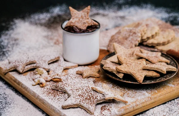 Star shaped christmas cookies decorated sugar and cocoa powder, a cup of hot chocolate. Close-up shot.