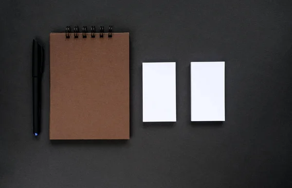 A sketchpad with brown pages and empty business cards on a black background